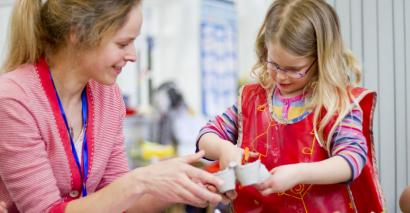 Teacher helping during a DT session for primary pupils cutting an egg box